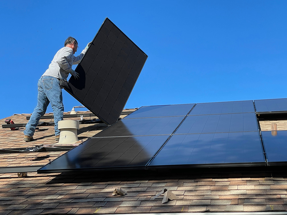 A man installing solar panels on the roof.