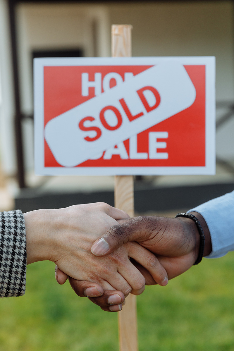 Two men shake hands after the sale of a house.