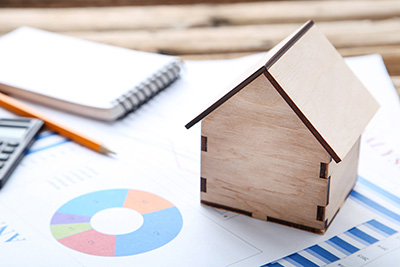A small wooden miniature house sitting on a paper with a graph on it.