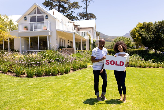 young couple standing in front of new investment property purchased through a 1031 exchange