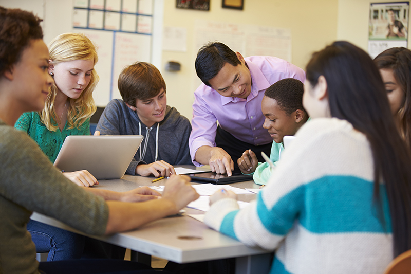 students sitting around a table learning from their teaching in a good school district 